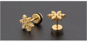 Macro de boucles d'oreilles flocon dorées avec texture mate et fermoir haltère sur fond noir