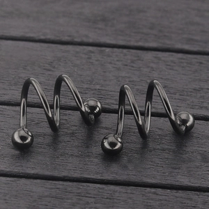 Pair of black titanium steel spiral body piercing jewelry for nose or lip on wood