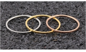 Minimalistische Edelstahlringe in Silber, Gold und Roségold auf einer schwarzen Steinfläche