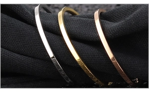 Makroansicht flacher, polierter Armreifen in Silber, Gold und Roségold-Finish