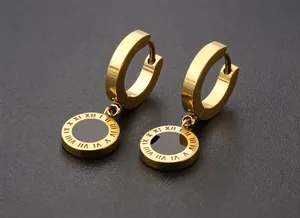 Close-up of golden stainless steel hoop earrings with Roman numeral engraved disc pendants