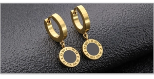 Macro shot of gold-plated roman numerals and black disk detail on titanium steel earrings