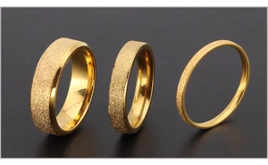 Close-up of three gold matte stainless steel rings showing sandblasted texture and polished interior