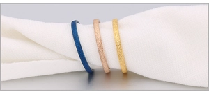 Detailed view of matte stackable rings in navy blue, rose gold, and gold finishes