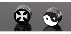 Primer plano de pendientes magnéticos de acero con cruz de hierro y símbolo yin yang