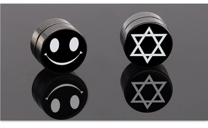 Vista macro de pendientes magnéticos negros con símbolos minimalistas de sonrisa y hexagrama