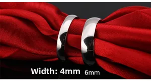 Polished silver titanium steel rings shown in 4mm and 6mm widths on red silk
