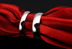 Close-up of two polished silver titanium steel rings on elegant red satin fabric background