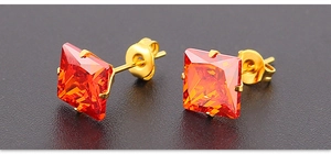 Detalle de pendientes cuadrados de circonita naranja en acero de titanio dorado