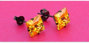 Vue macro de boucles d'oreilles en zircone jaune carrée avec griffes en métal noir