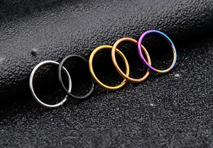 Makroaufnahme von Piercingringen aus Edelstahl in fünf Metallic-Farben auf dunklem Grund