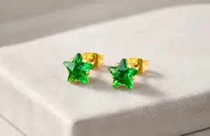 Détail de boucle d'oreille étoile en acier titane doré avec zircon vert et griffes