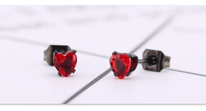Vue macro des boucles d'oreilles cœur en zircon rouge et base en acier inoxydable noir
