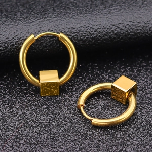 Pair of gold stainless steel hoop earrings with solid cube charms on black textured base