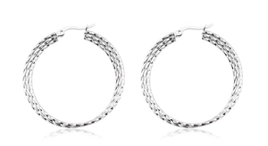 Close-up of large silver hoop earrings featuring twisted texture and polished finish