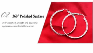 Macro detail of silver hoop earrings with textured finish on elegant red silk background