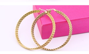 Detail view of large gold hoop earrings featuring a sophisticated woven spiral texture