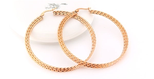 Detailed macro view of large rose gold hoop earrings with intricate woven texture finish