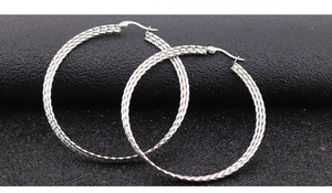 Detailed macro shot of silver hoop earrings featuring intricate woven texture and metallic luster