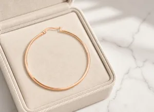 Polished rose gold stainless steel hoop earring featuring a classic round circular design