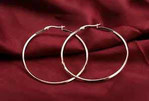 Macro shot of large rose gold hoop earrings on red silk background with a click-top closure