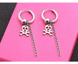 Detailaufnahme silberner Totenkopf-Ohrring mit langer Kette auf rosa Geschenkbox