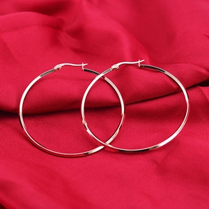 Polished gold stainless steel oversized hoop earrings on a textured red satin background