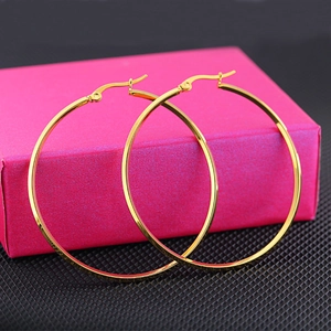 Polished gold stainless steel oversized geometric hoop earrings on a pink jewelry box