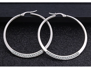 Detalle de pendientes de aro plateados pulidos con circonitas brillantes incrustadas