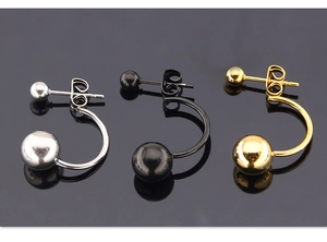 Detalle de pendientes minimalistas de doble bola en plata, oro y acero negro