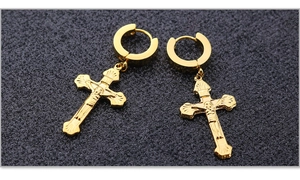 Detalle macro de los pendientes colgantes con cruz de crucifijo en acero dorado