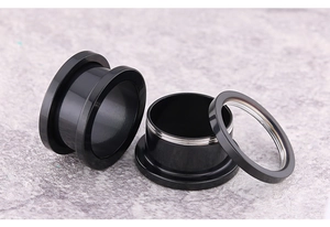 Macro detail of black stainless steel ear tunnels with screw thread design and polished finish