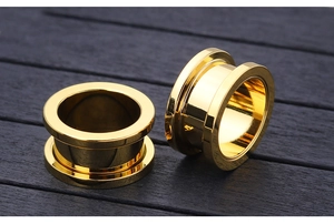 Macro detail of high-polish gold titanium steel ear tunnels with mirror finish