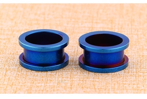 Macro detail of blue gradient electroplated stainless steel ear tunnels on fabric