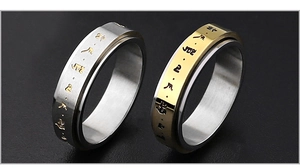 Detalle de anillos giratorios de acero inoxidable con mantras budistas grabados en bicolor