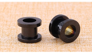 Macro shot of two black polished stainless steel hollow tunnels for ear piercing