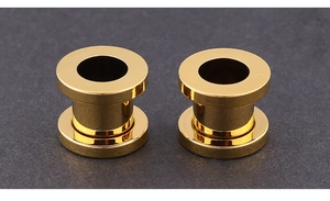 Close-up of golden hollow ear tunnels made of polished stainless steel with reflective finish