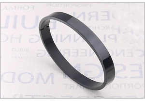 Detail of minimalist black stainless steel oval bangle with high-gloss finish and side clasp