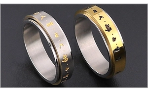 Detalle de anillos giratorios de acero de titanio con símbolos sánscritos grabados y acabado bicolor
