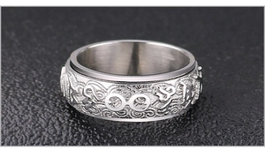 Vista macro de anillo giratorio de plata con símbolos de mantra budista grabados