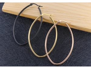 Macro shot of oval hoop earrings in black, gold, and rose gold with a secure snap closure