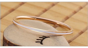 Vue macro d'une bague en acier titane or rose avec émail blanc sur un support en bois