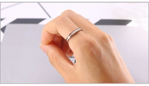 Détail d'une bague fine 2mm en acier inoxydable or rose avec émail noir portée au doigt