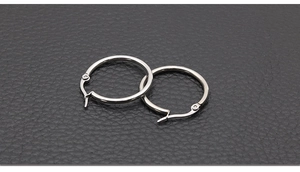 Detailed macro view of polished stainless steel hoop earrings with secure hinge closures
