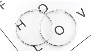 Macro detail of large polished stainless steel hoop earrings with a secure clasp closure