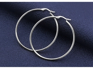 Macro detail of large polished silver hoop earrings with secure clasp closure