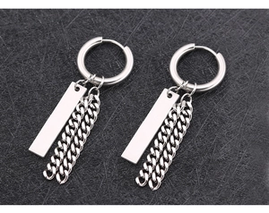 Détail macro de boucles d'oreilles punk en acier avec breloques croix et chaînes en métal