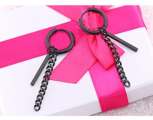 Gros plan de boucles d'oreilles punk noires avec chaîne sur boîte cadeau blanche