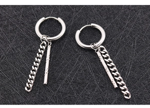 Détail des boucles d'oreilles punk argentées avec chaîne cubaine et pendentif bar