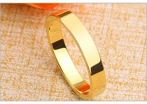 Close-up of a wide gold-plated stainless steel band with high-polish mirror finish